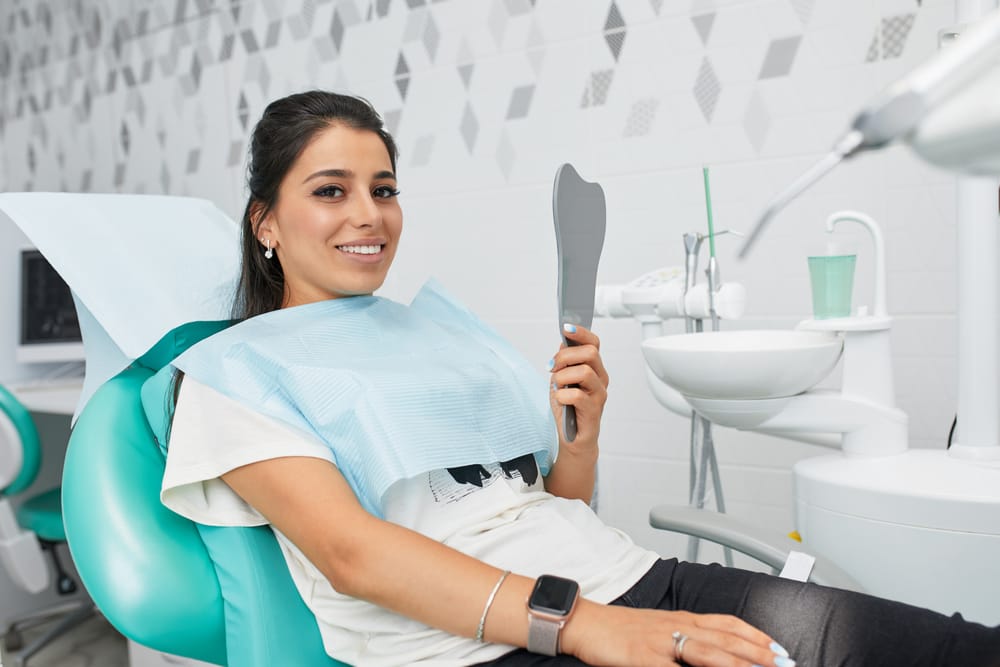 Woman holding a mirror at the dentist - Tooth Implant Tucson AZ