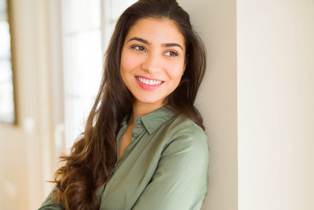 Woman leaning on a wall smiling - Botox Oro Valley