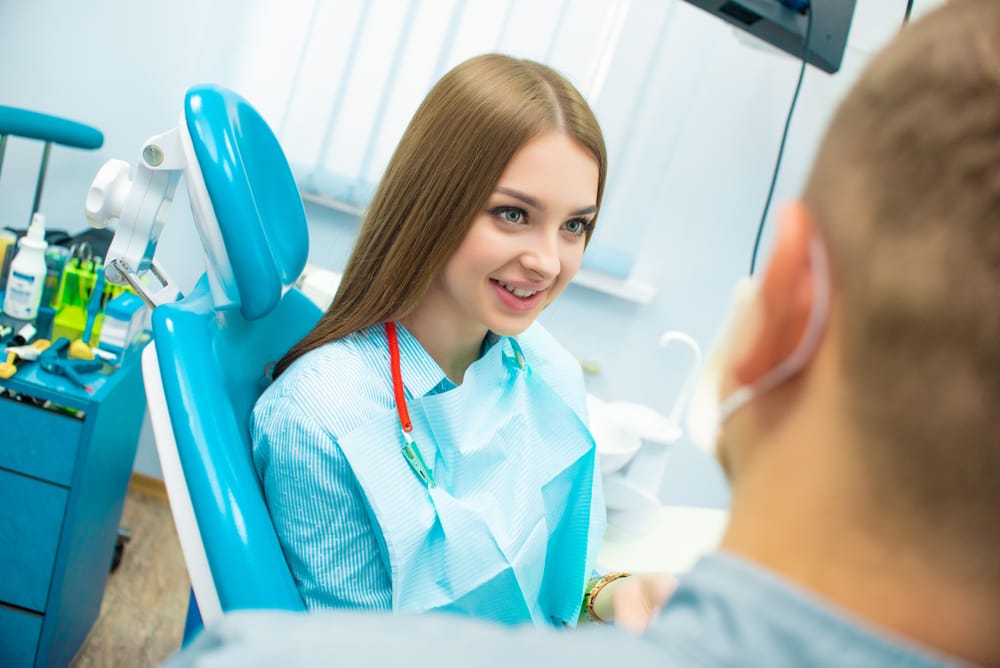 Beautiful emotional girl sitting in a dental chair next to a male doctor - Sedation Dentistry Tucson AZ