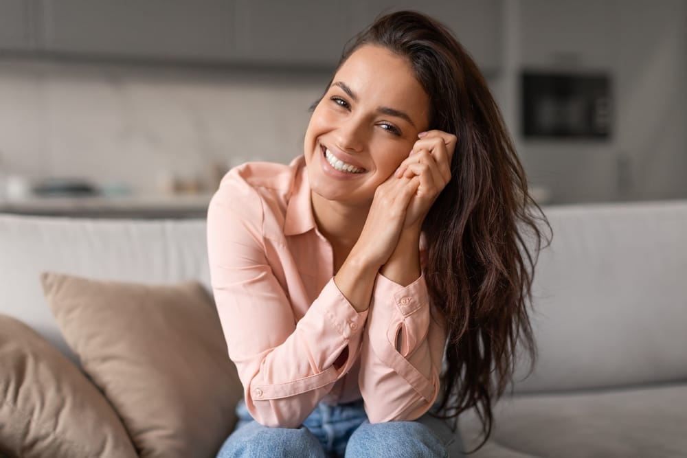 Woman smiling while sitting on a sofa - Botox Tucson